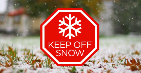 A red Keep Off snow sign placed on the ground.